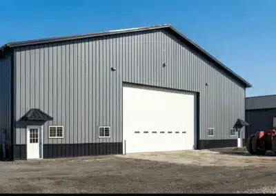 Commercial grey steel post-frame warehouse with tractor outside