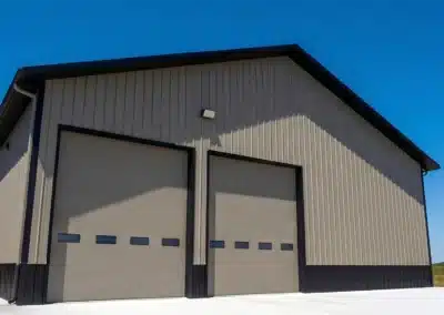 Double bay steel farm garage with brown trim under clear blue sky.