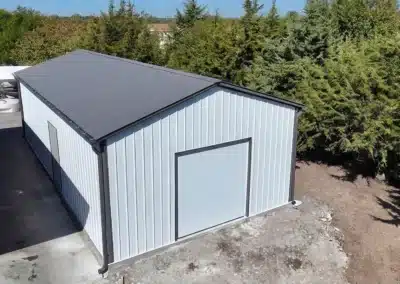 Steel pole barn garage with grey roof in a wooded area
